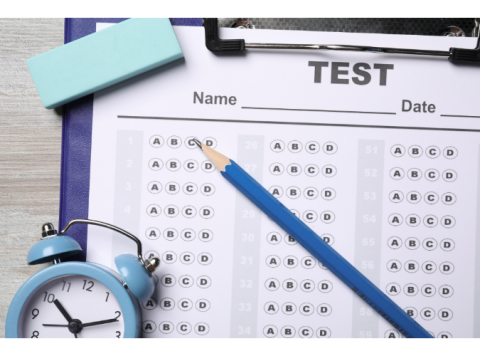 A blue clipboard with a blank test, an eraser, a pencil and a timer. 